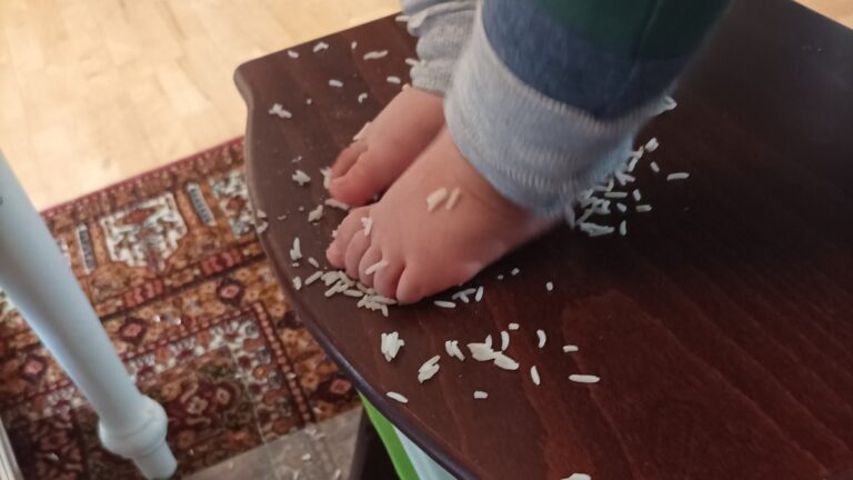 Baby beim Baby-led Weaning mit Reis am Familientisch